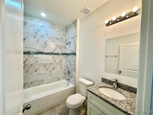 full bathroom with a textured ceiling, vanity, toilet, and tiled shower / bath