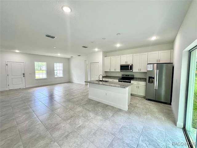 kitchen with light stone countertops, white cabinetry, an island with sink, and appliances with stainless steel finishes