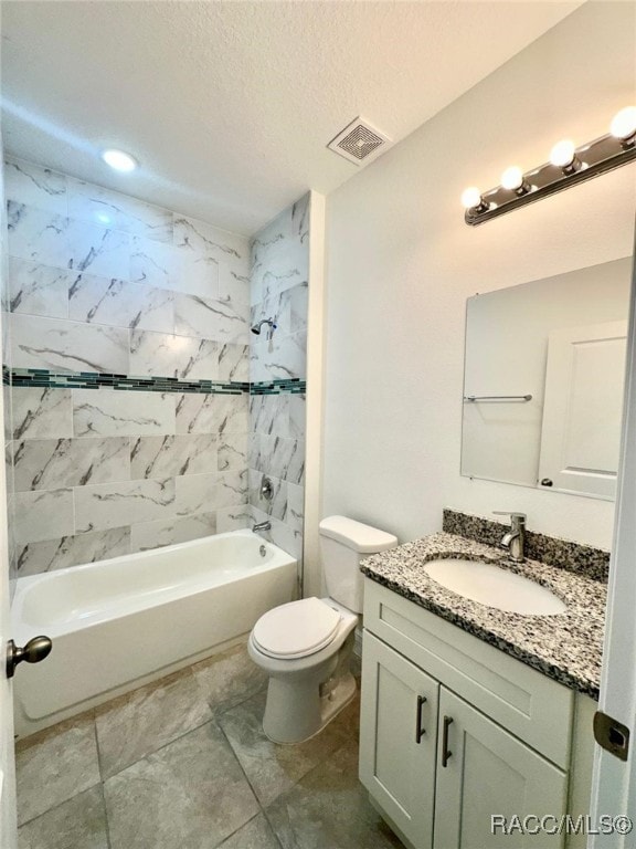 full bathroom featuring vanity, a textured ceiling, tile patterned flooring, toilet, and tiled shower / bath