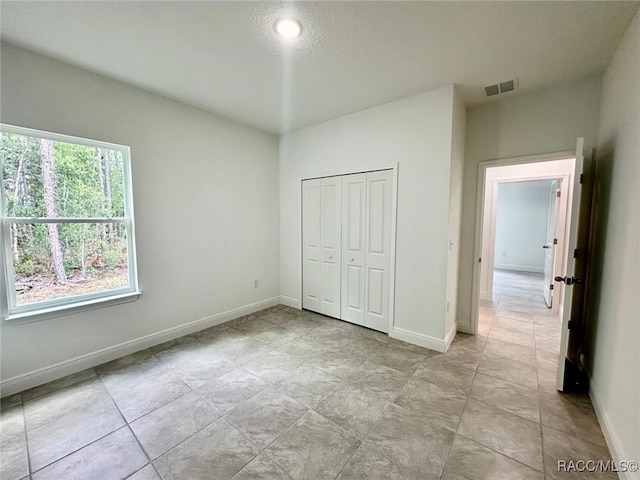 unfurnished bedroom featuring a textured ceiling and a closet