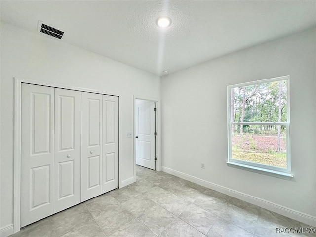 unfurnished bedroom with a textured ceiling and a closet