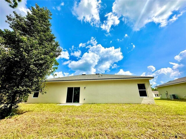 rear view of property featuring a lawn and cooling unit