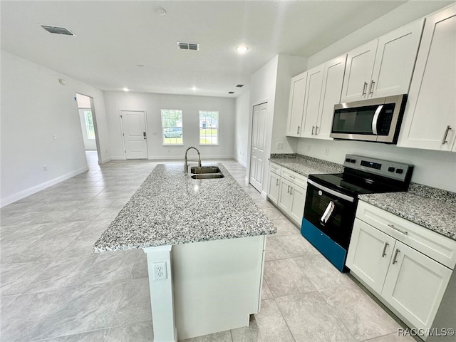 kitchen with a kitchen island with sink, sink, light stone countertops, white cabinetry, and stainless steel appliances