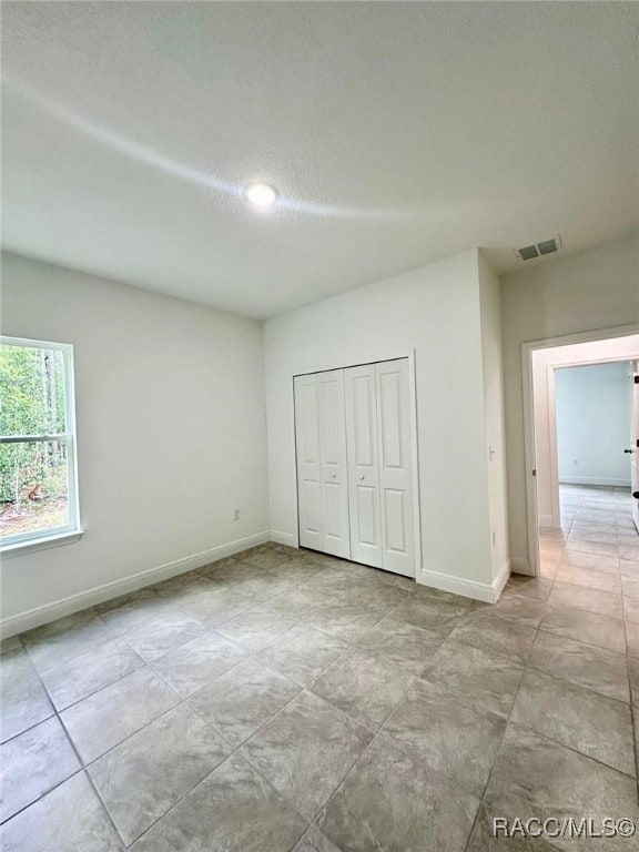 unfurnished bedroom with a textured ceiling and a closet