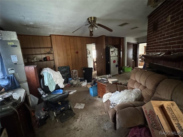 living room featuring wooden walls, visible vents, and a ceiling fan