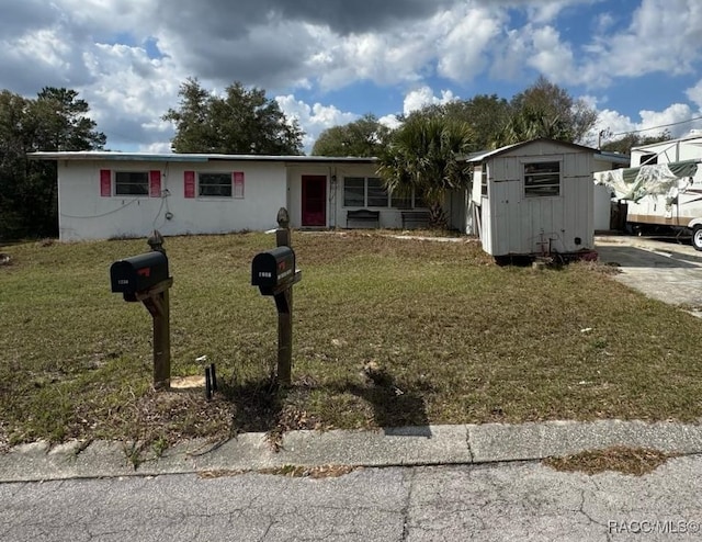 view of front of property featuring a storage shed and a front yard