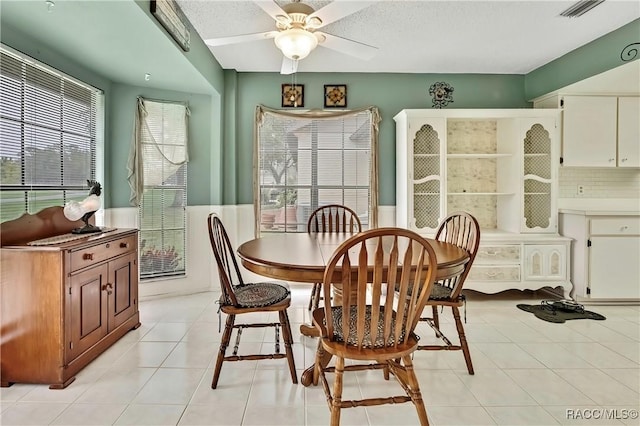 dining area with a textured ceiling, light tile patterned flooring, visible vents, and a ceiling fan