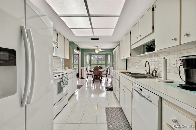 kitchen featuring light tile patterned floors, white appliances, a sink, white cabinets, and light countertops