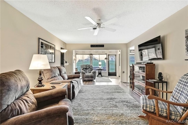 living room featuring a ceiling fan, a textured ceiling, and wood finished floors