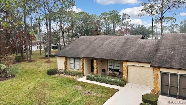 view of front facade featuring stone siding, an attached garage, driveway, and a front yard