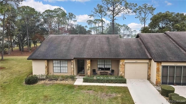 multi unit property featuring stone siding, a front lawn, an attached garage, and driveway