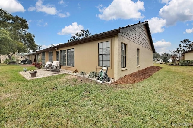 view of property exterior with a yard, a patio, and stucco siding