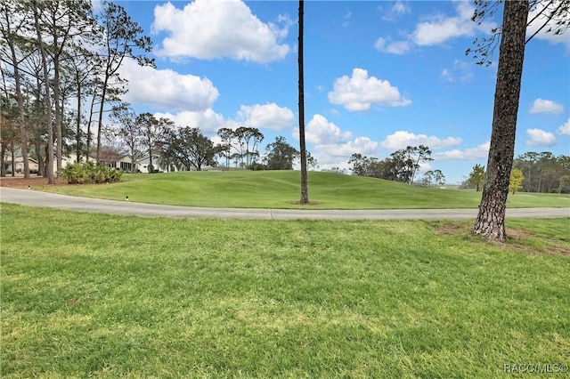 view of property's community featuring view of golf course and a yard