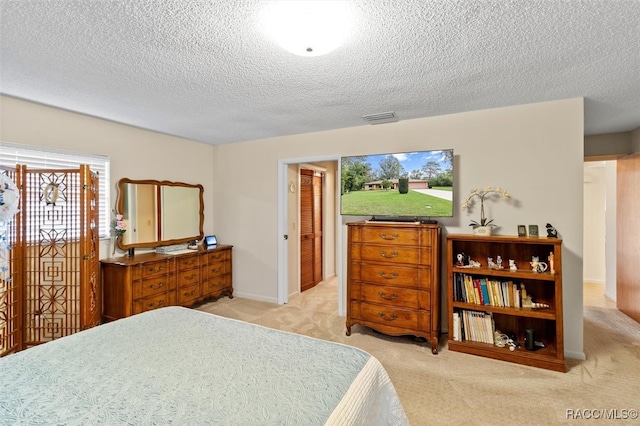 bedroom with light colored carpet and a textured ceiling