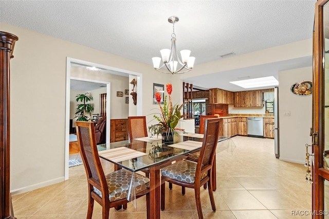 dining space featuring a notable chandelier, a textured ceiling, and light tile patterned floors