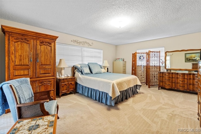 bedroom with multiple windows, light carpet, and a textured ceiling