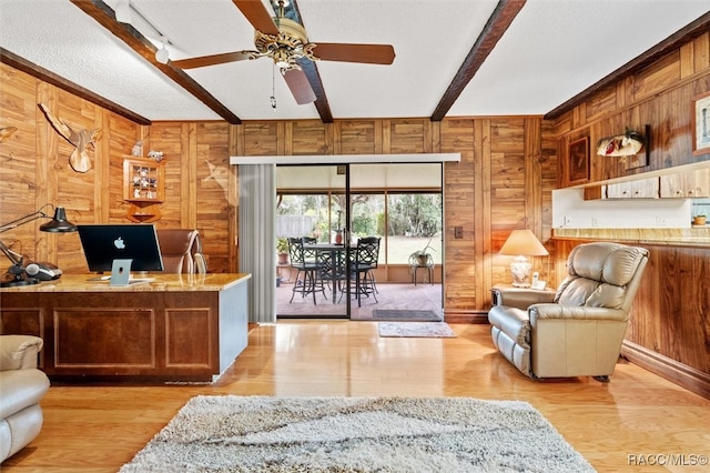 home office with wooden walls, track lighting, a textured ceiling, beam ceiling, and light hardwood / wood-style flooring