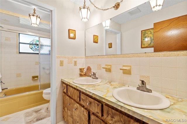 full bathroom featuring shower / bath combination with glass door, tile walls, vanity, tile patterned floors, and toilet