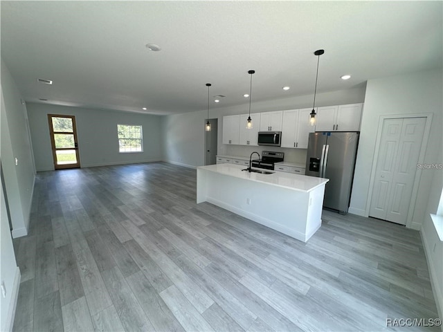 kitchen featuring sink, white cabinets, hanging light fixtures, a kitchen island with sink, and stainless steel appliances