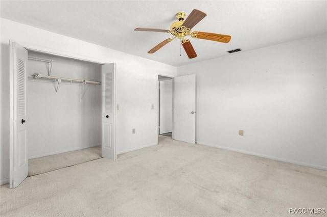 unfurnished bedroom featuring a closet, light colored carpet, and ceiling fan