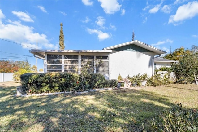 view of property exterior with a sunroom and a yard