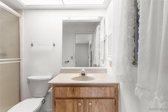 bathroom featuring vanity, a shower with shower door, and toilet