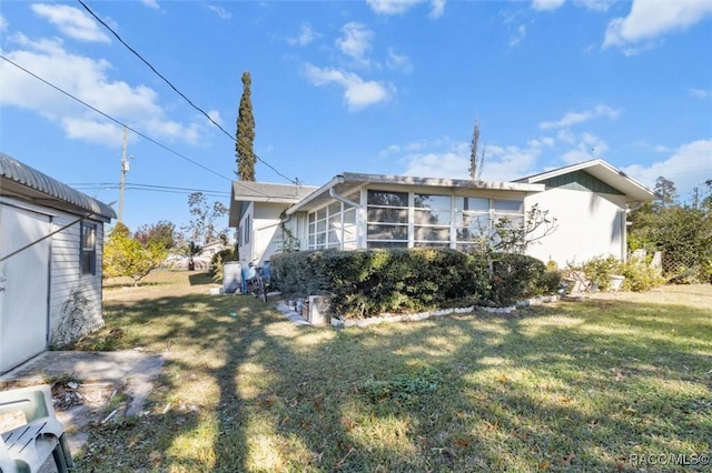 rear view of house with a lawn and a sunroom