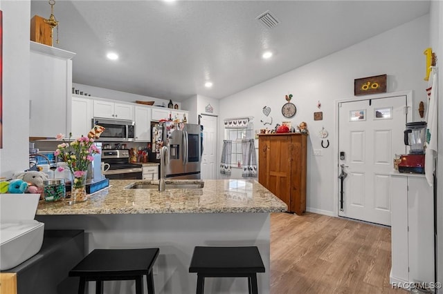 10541 S Drew Bryant Cir, Floral City, FL 34436 - kitchen featuring light wood finished floors, white cabinets, a peninsula, appliances with stainless steel finishes, and light stone countertops
