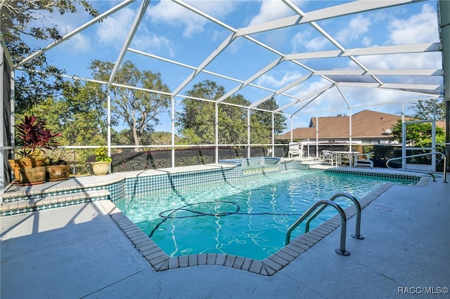 view of swimming pool with glass enclosure and a patio area