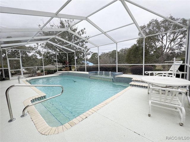 view of swimming pool with glass enclosure, a patio area, and a jacuzzi