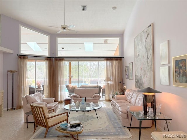 tiled living room with ceiling fan and a towering ceiling