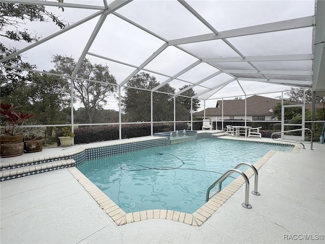 view of pool with glass enclosure and a patio area