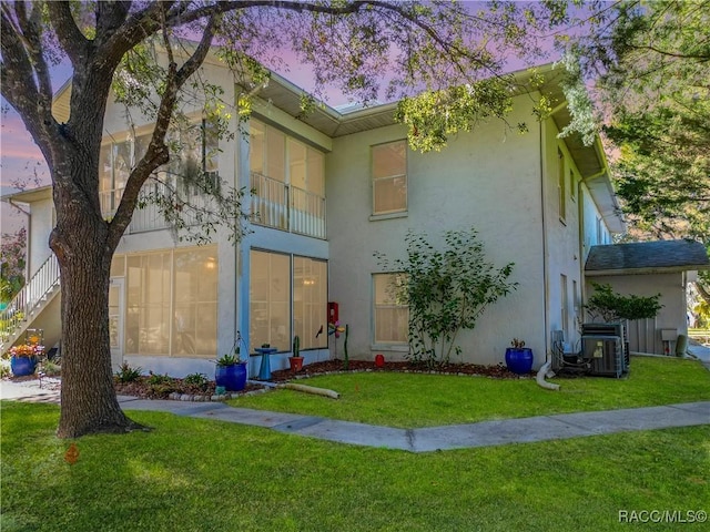 view of front of property with central AC unit and a lawn