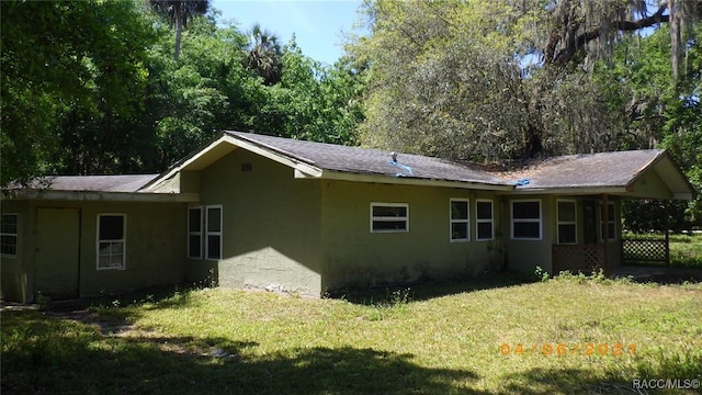 back of house featuring a yard, stucco siding, and an attached carport
