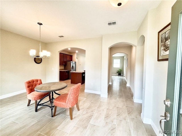 dining space featuring arched walkways, visible vents, baseboards, and an inviting chandelier