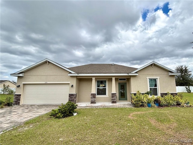 view of front facade featuring a front yard, decorative driveway, an attached garage, and stucco siding