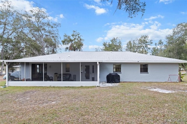 rear view of property with a lawn and a sunroom