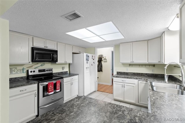 kitchen featuring a textured ceiling, sink, white refrigerator with ice dispenser, electric stove, and white cabinets