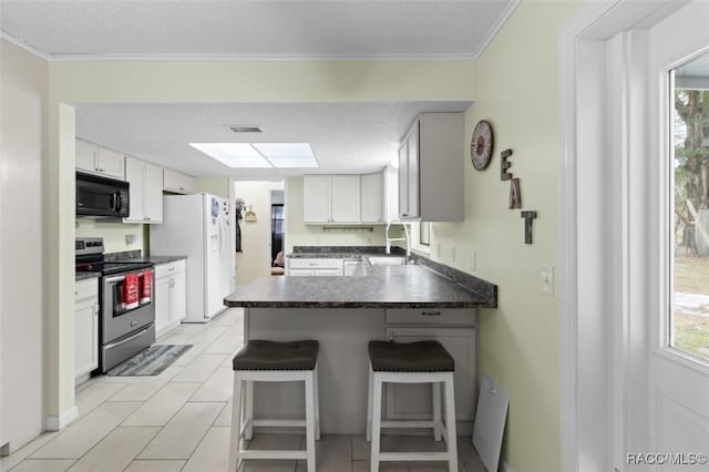 kitchen featuring a breakfast bar, electric range, white cabinetry, and a healthy amount of sunlight