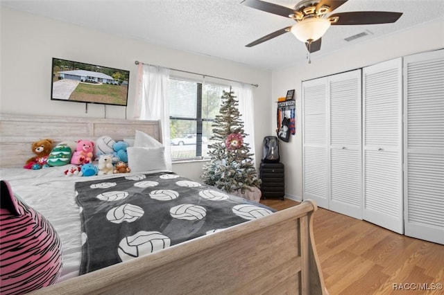 bedroom with a closet, a textured ceiling, light hardwood / wood-style floors, and ceiling fan