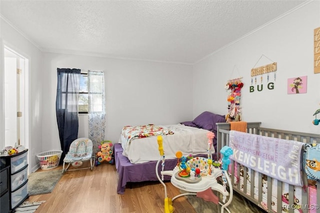 bedroom with a textured ceiling, light hardwood / wood-style floors, and crown molding