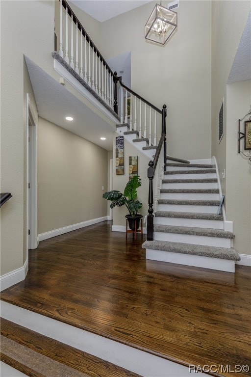 staircase with hardwood / wood-style flooring and a notable chandelier