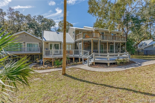 rear view of house featuring a yard, a sunroom, a balcony, and a wooden deck