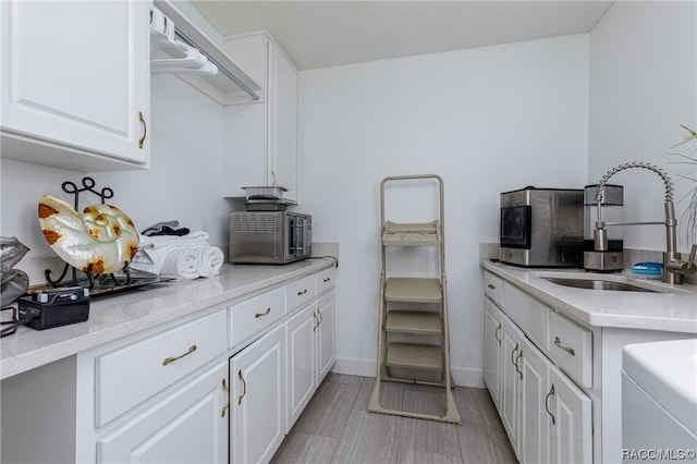 kitchen with white cabinets, light stone counters, and sink