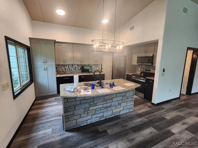 kitchen featuring dark hardwood / wood-style flooring, high vaulted ceiling, stainless steel appliances, and decorative light fixtures