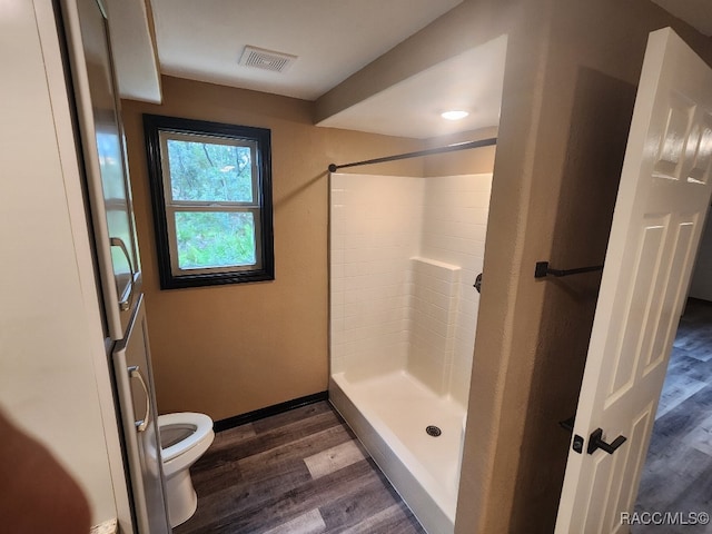 bathroom with a shower, wood-type flooring, and toilet