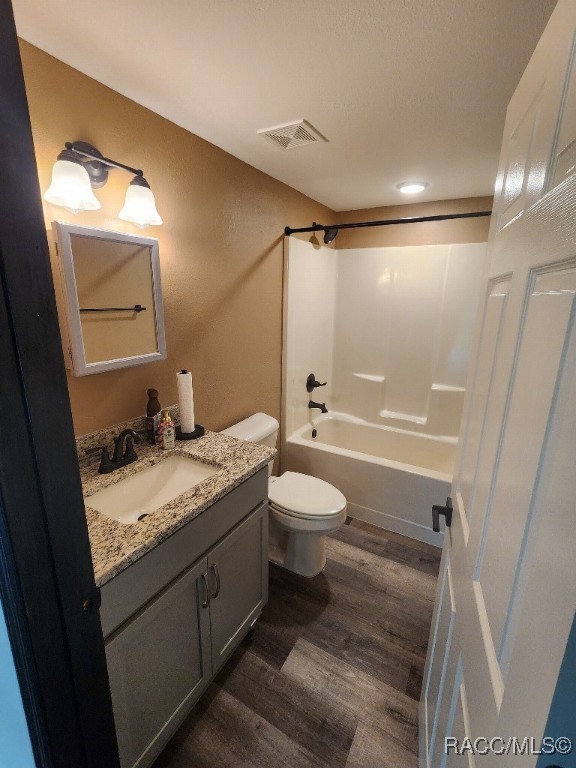 full bathroom featuring shower / bathing tub combination, vanity, hardwood / wood-style flooring, and toilet