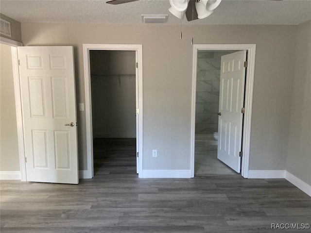 unfurnished bedroom with a spacious closet, a textured ceiling, a closet, and ceiling fan