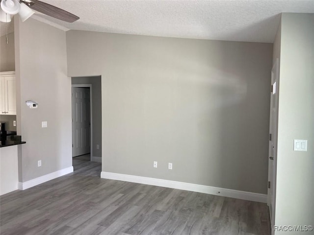 unfurnished room featuring ceiling fan, lofted ceiling, hardwood / wood-style floors, and a textured ceiling