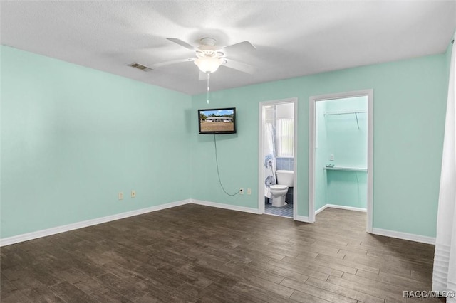 empty room featuring visible vents, baseboards, dark wood-style floors, and a ceiling fan